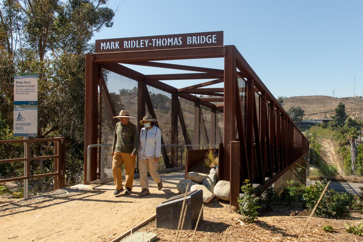 Hikers walk across a bridge. 