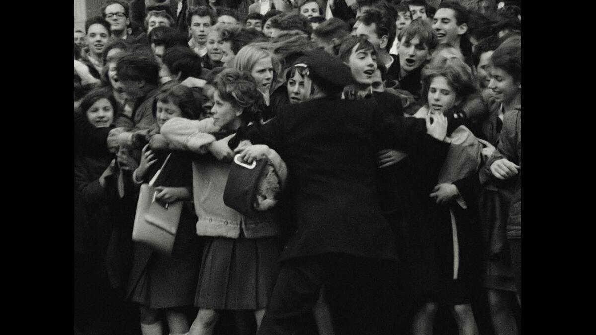 A single police officer with arms outstretched as dozens of teens crowd in front of him.