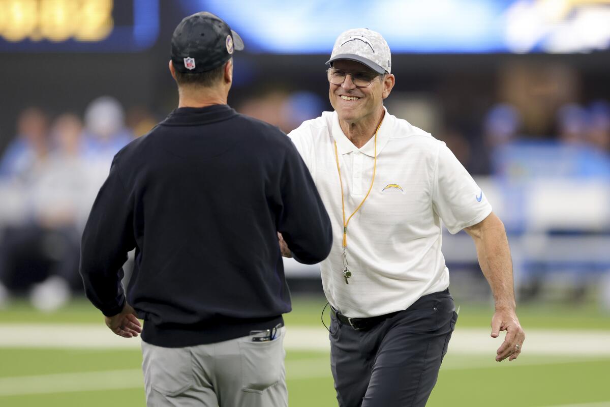 Chargers coach Jim Harbaugh (right) greets brother John, coach of the Ravens, before their Monday night game. 