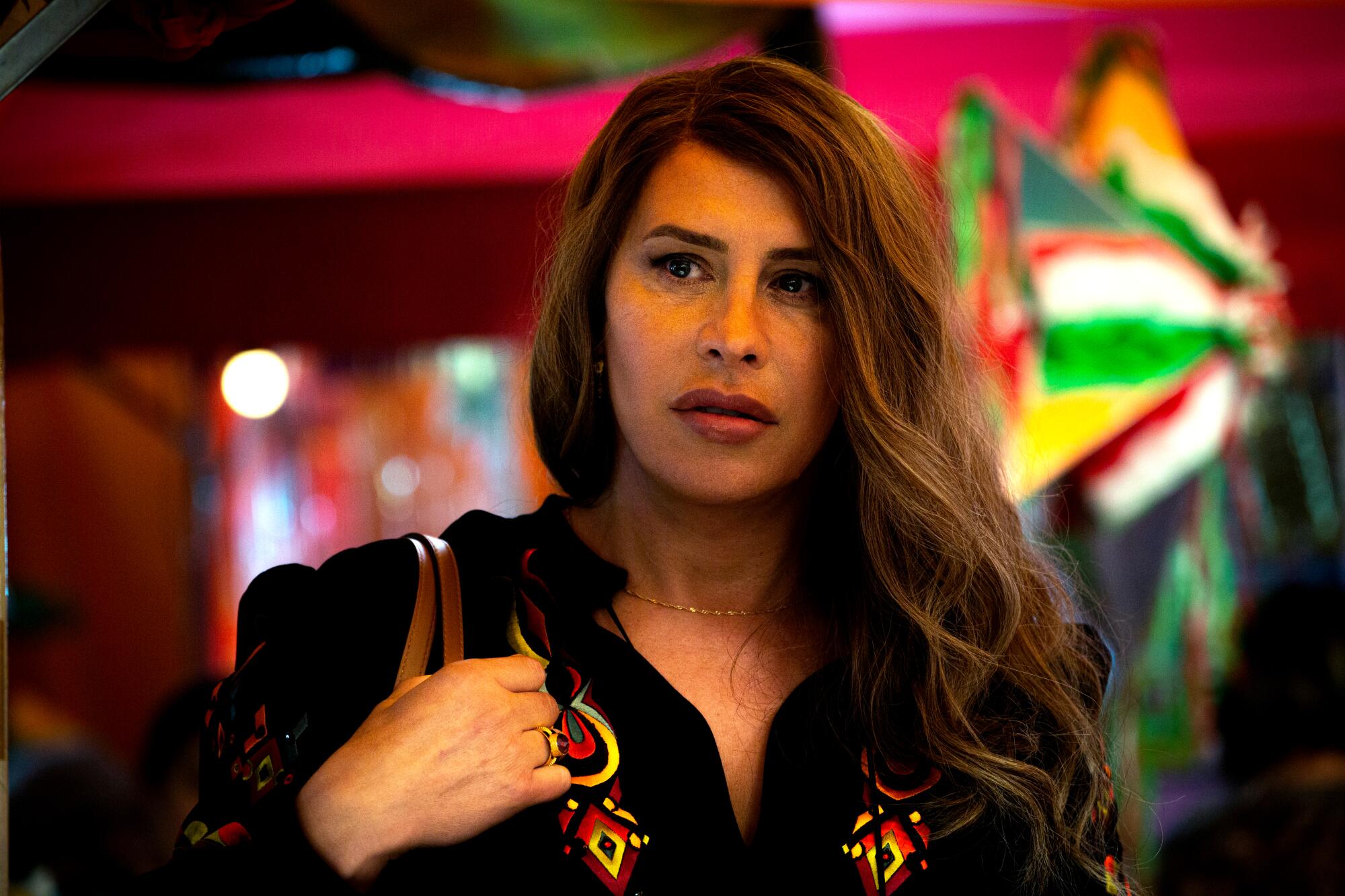 A woman walks past a brightly colored background in "Emilia Pérez."