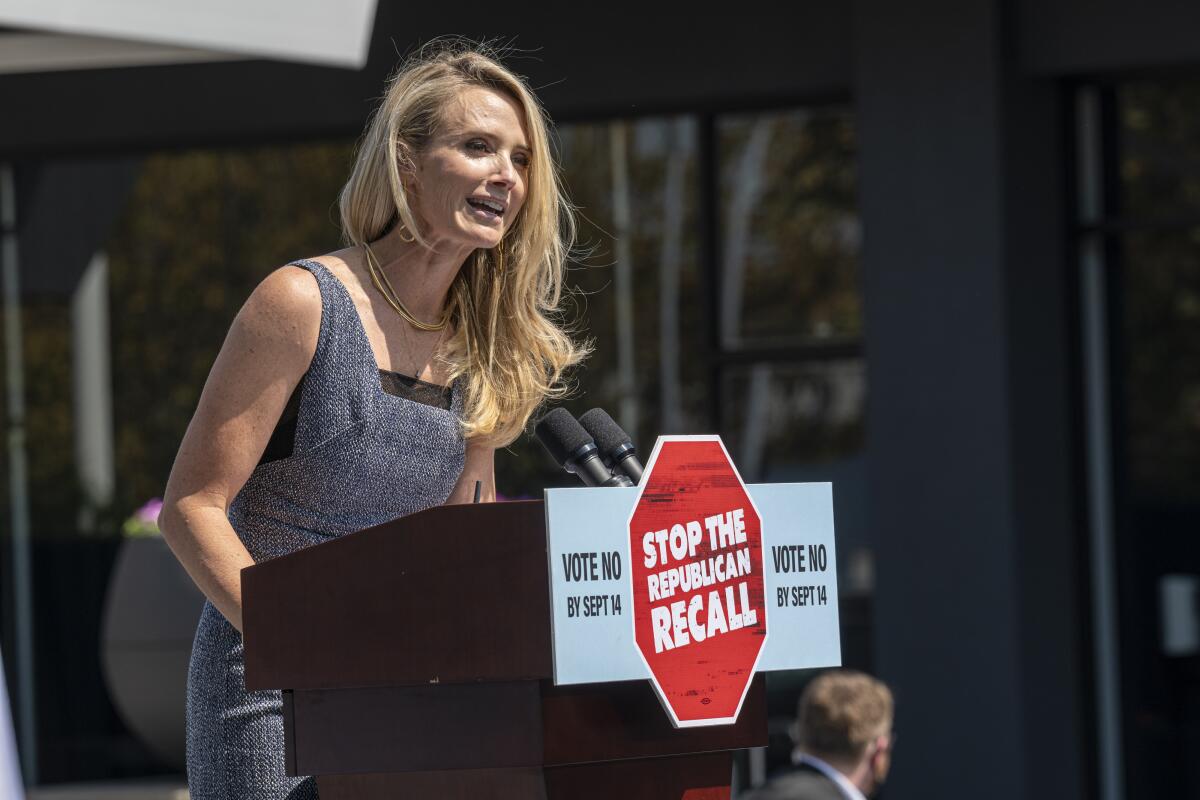 Jennifer Siebel Newsom speaking from a lectern bearing a sign with a red octagon reading "Stop the Republican recall"