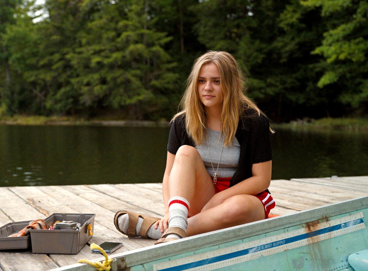 A young woman sits on a dock.