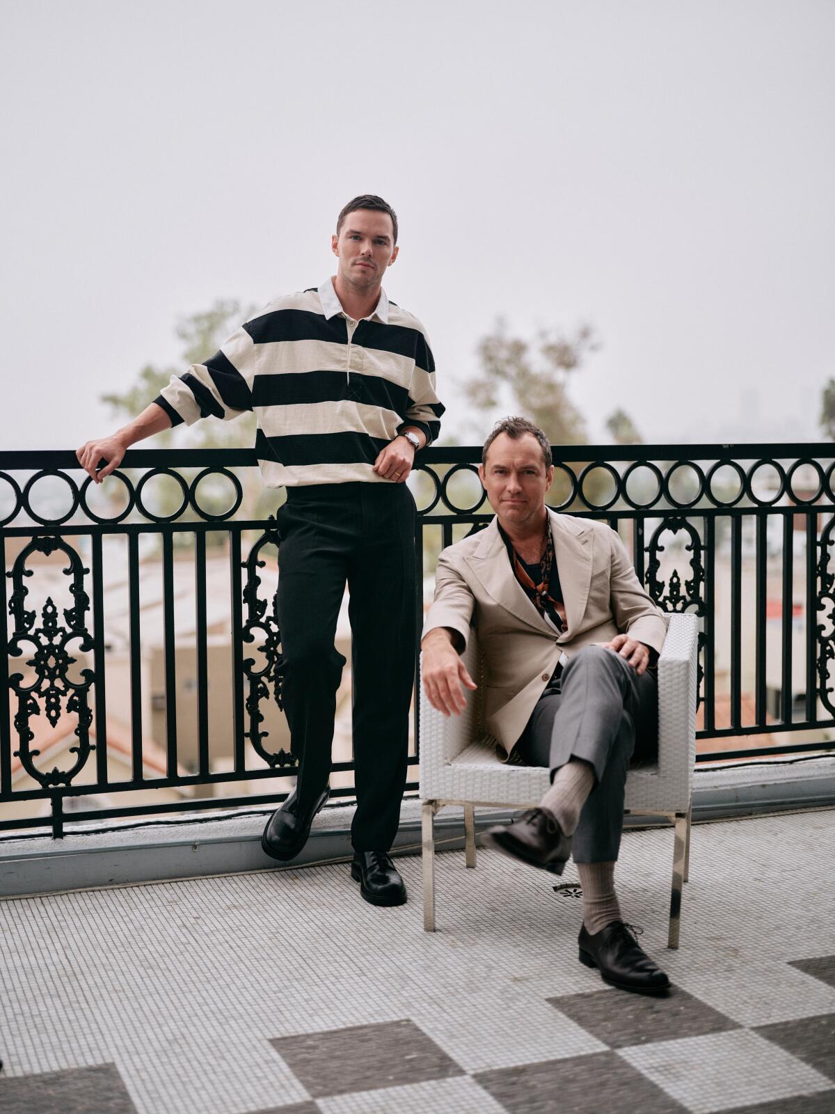 Two actors pose on a balcony at a hotel.