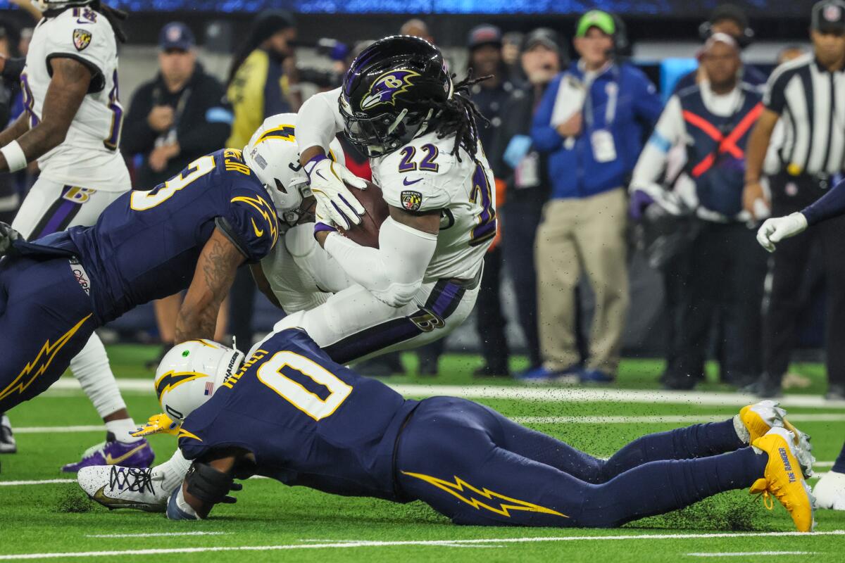 Chargers safety Derwin James Jr., left, and linebacker Daiyan Henley (0) tackle Ravens running back Derrick Henry