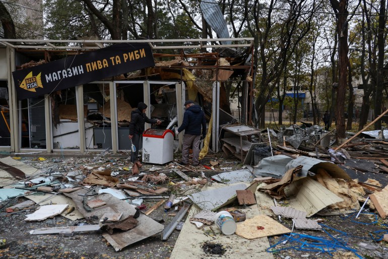 Resident remove debris from a shop heavily damaged by a Russian drone strike