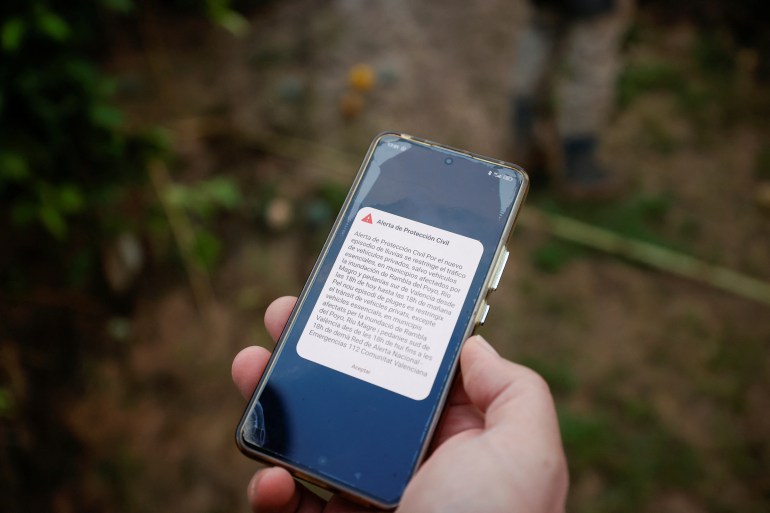 A person holds a mobile phone showing an alert that announces traffic restrictions in 20 municipalities affected by the overflowing of the Poyo wadi and the Magro river due to the DANA, in Quart de Poblet, Valencia, Spain, November 13, 2024. REUTERS/Eva Manez