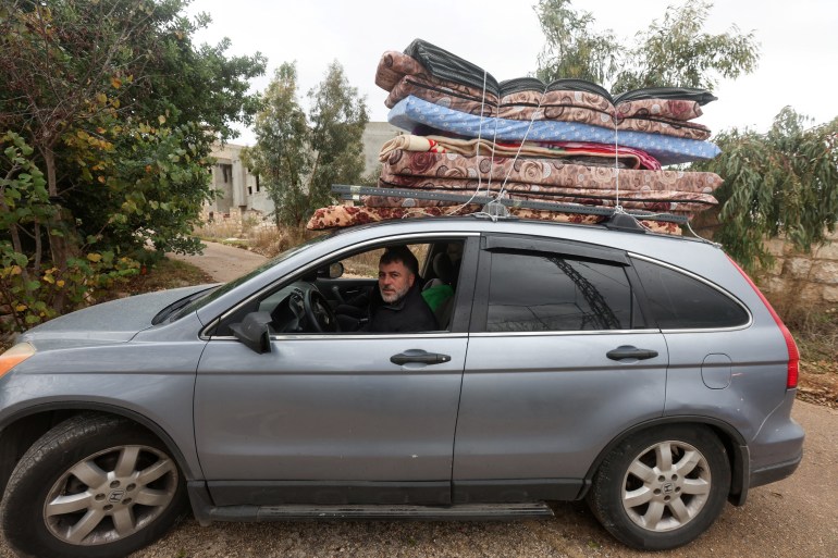 Displaced Lebanese Assaad Bzih is pictured in his car with belongings on the top of his car, near his destroyed home, after a ceasefire between Israel and Hezbollah took effect,