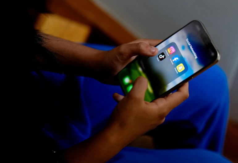 A high school student poses with her mobile showing her social media applications 