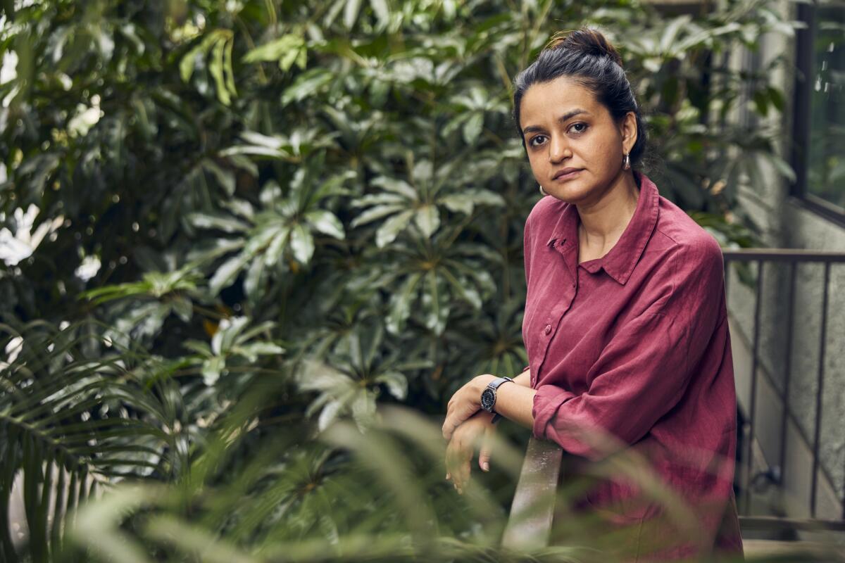 A woman stands on a bacony overlooking a garden.