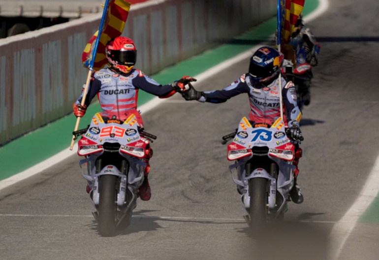 Ducati Spanish rider Marc Marquez (L) and his brother Ducati Spanish rider Alex Marquez hold Valencian flags as they ride their bikes after the MotoGP Solidarity Grand Prix of Barcelona at the Circuit de Catalunya on November 17, 2024 in Montmelo on the outskirts of Barcelona. - Jorge Martin won the MotoGP world title after taking a 24-point lead into the final weekend of the season in Barcelona. (Photo by Manaure Quintero / AFP)