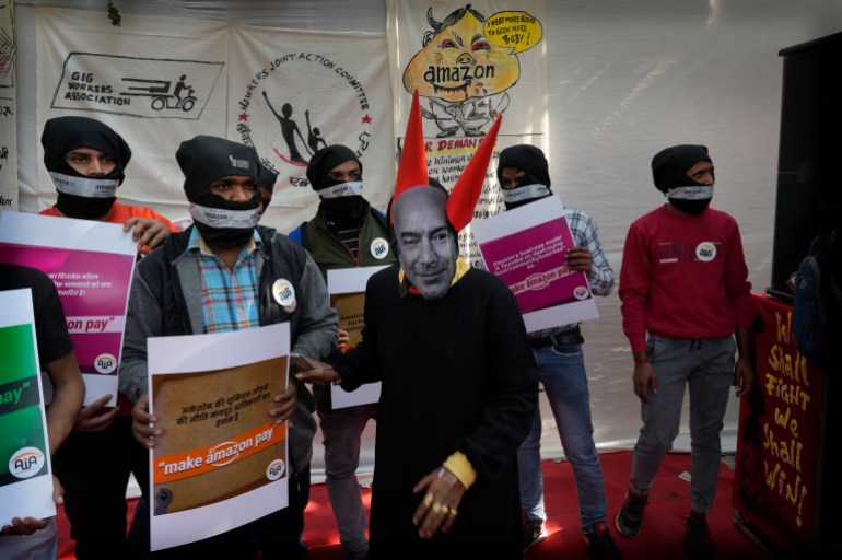 A woman dressed as Jeff Bezos, Executive Chairman of Amazon, and other Gig Workers Association (GigWA) and Amazon Warehouse workers participate in a protest in New Delhi, Friday, Nov. 25, 2022. The protest was against the alleged unfair treatment and work environment by multinational companies against their workers. (AP Photo/Manish Swarup)