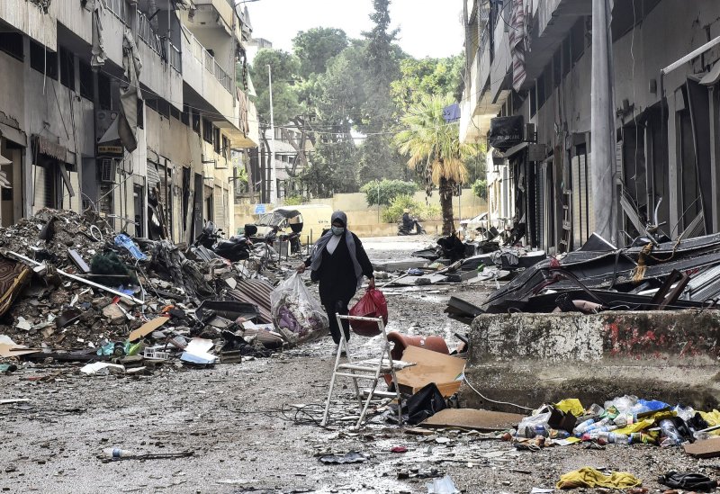 A Lebanese woman walk beside destroyed buildings at the site of an Israeli overnight airstrike that targeted the area of Tayouneh on the outskirts of Beirut's southern suburbs, on Tuesday. Early Wednesday, a cease-fire went into effect with hopes it will lay the foundation for a truce. Photo by Rahim Rhea/UPI