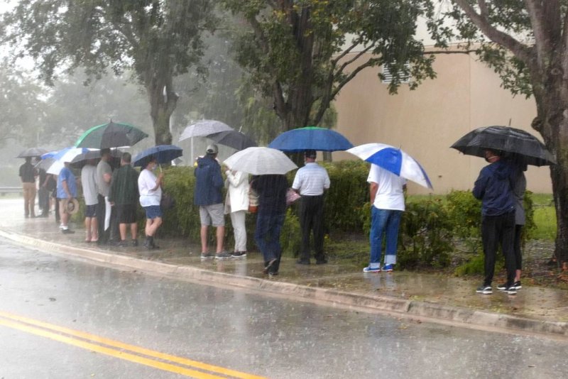 Voters wait in line under umbrellas during heavy rain showers to cast their ballots for the 2020 presidential election in Delray Beach, Fla. Tuesday's forecast calls for rain in several swing states, including Michigan, Wisconsin and parts of Pennsylvania. File Photo by Gary I Rothstein/UPI