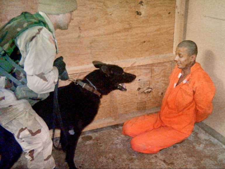 In this undated still photo, an Iraqi detainee at Abu Ghraib Prison appears to be intimidated by a U.S. soldier using an trained dog.