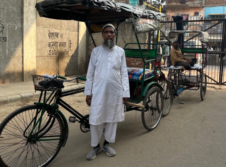 Sheikh Ali standing next to his rickshaw in New Delhi, India [Yashraj Sharma/ Al Jazeera]