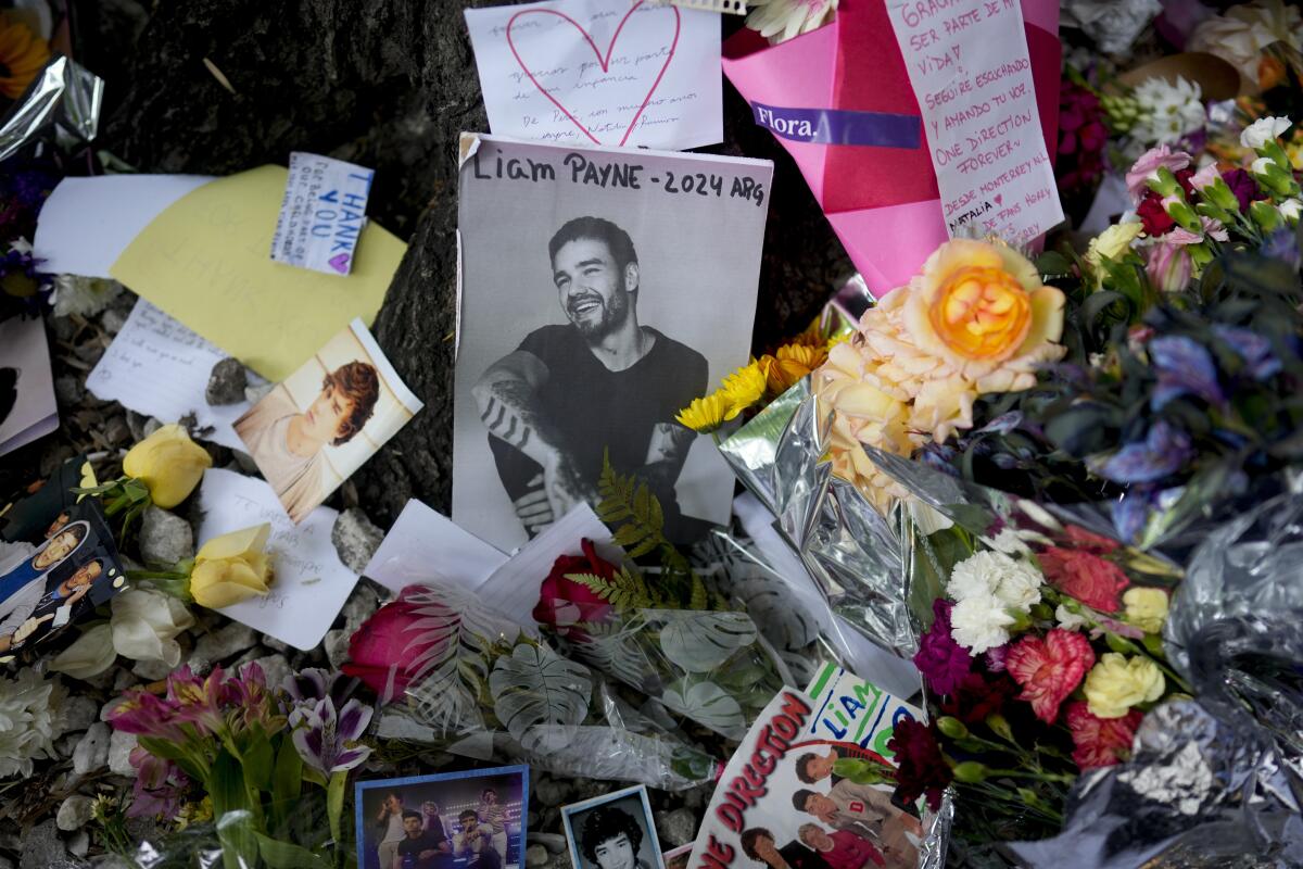 A photo of Liam Payne is nestled among flowers and other tribute items at a memorial for the singer in Argentina