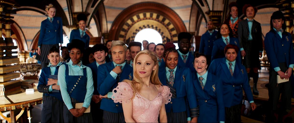 Ariana Grande wears a frothy pink at the head of fellow students all in uniform in "Wicked."