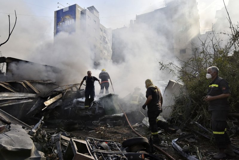 Firefighters stands amid the smouldering debris at the site of overnight Israeli airstrikes that targeted the neighborhood of Kafaat in Beirut's southern suburbs on Friday. The Israel Defense Forces confirmed they arrested a high-ranking Hezbollah naval commander during a raid the same day in northern Lebanon. Photo by Fadel Itani/UPI