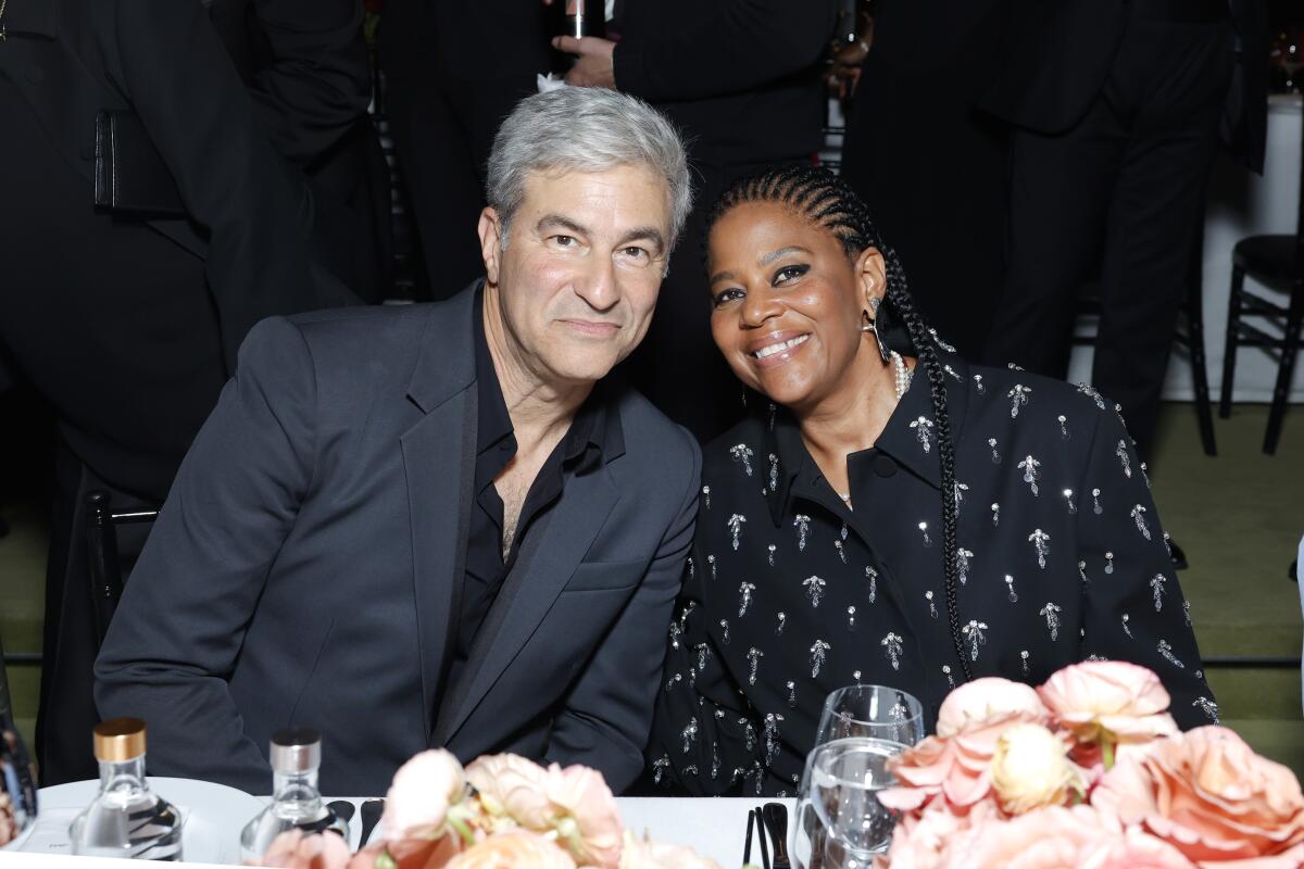 A gray-haired man leans in next to a smiling woman.