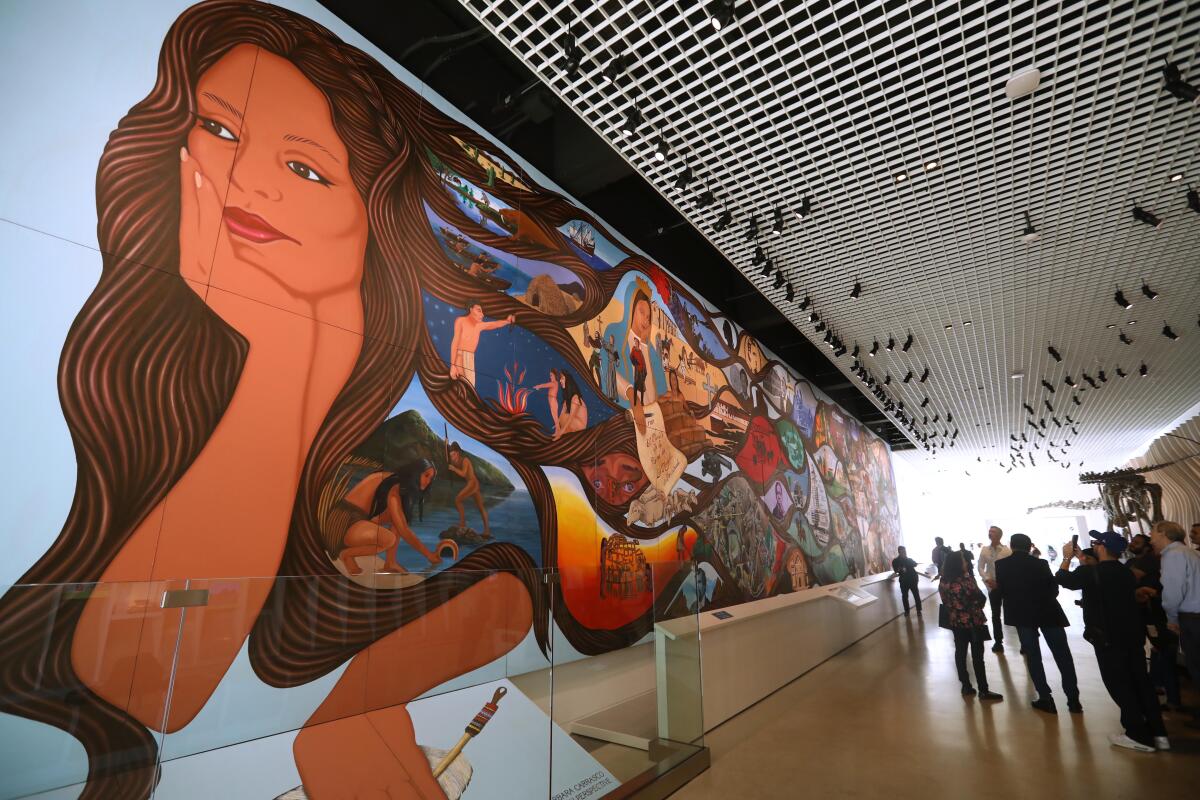 A mural featuring a woman with flowing hair that includes scenes of Los Angeles life