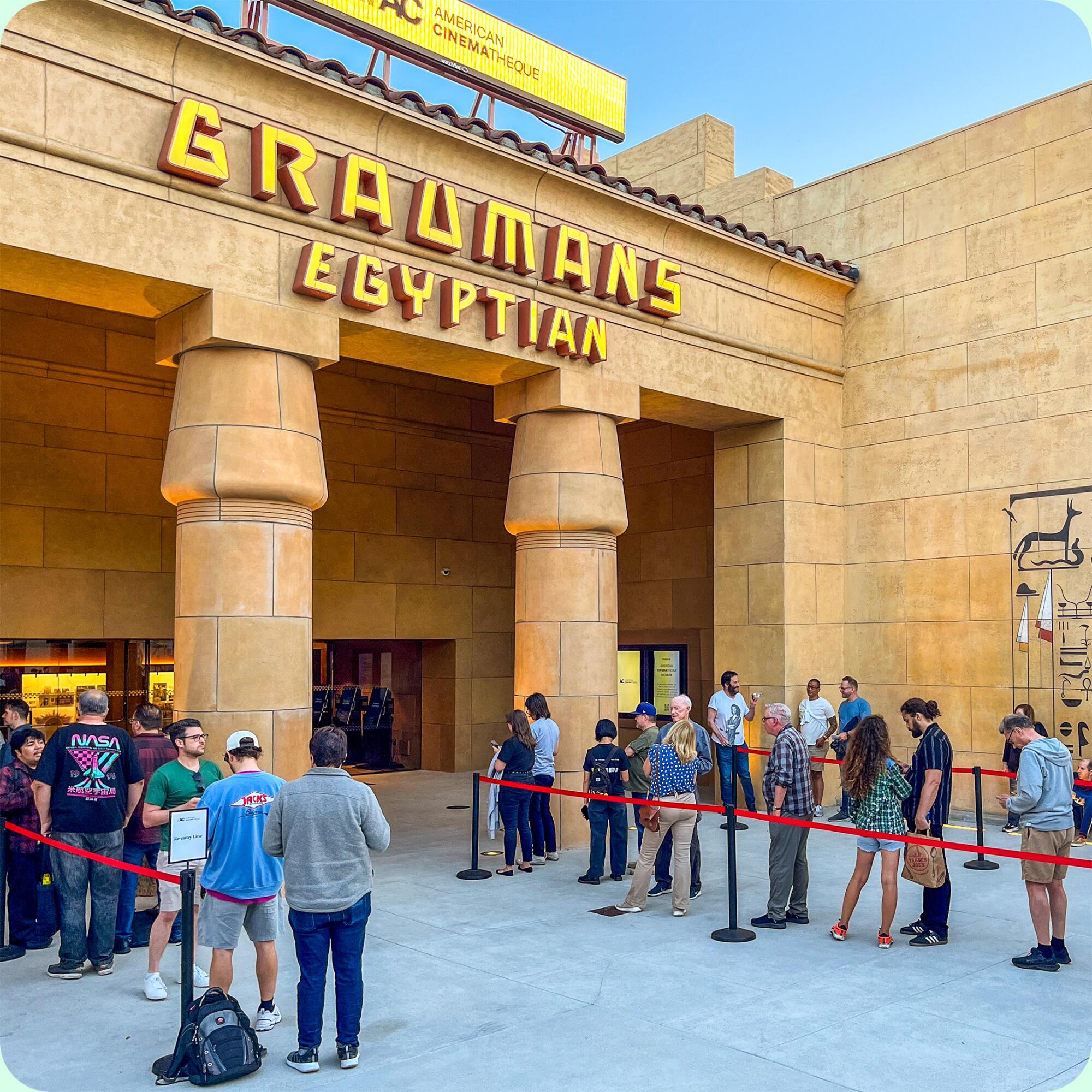 People line up to enter a theater under a Graumans Egyptian sign