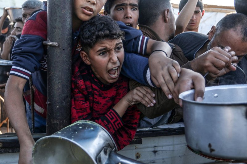 A Palestinian child screams amid the crowd while trying to receive food cooked by a charity kitchen amid food shortages in the southern Gaza Strip on Wednesday. On the same day, the United States vetoed a UN Security Council resolution calling for a cease-fire in Gaza. Photo by Anas Deeb/UPI