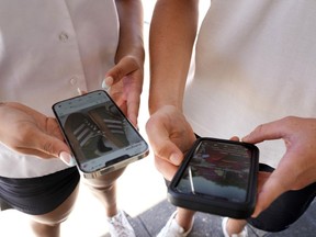 14-year-old Henry, right, and Angel, 15, use their phones to view social media in Sydney, Friday, Nov. 8, 2024.