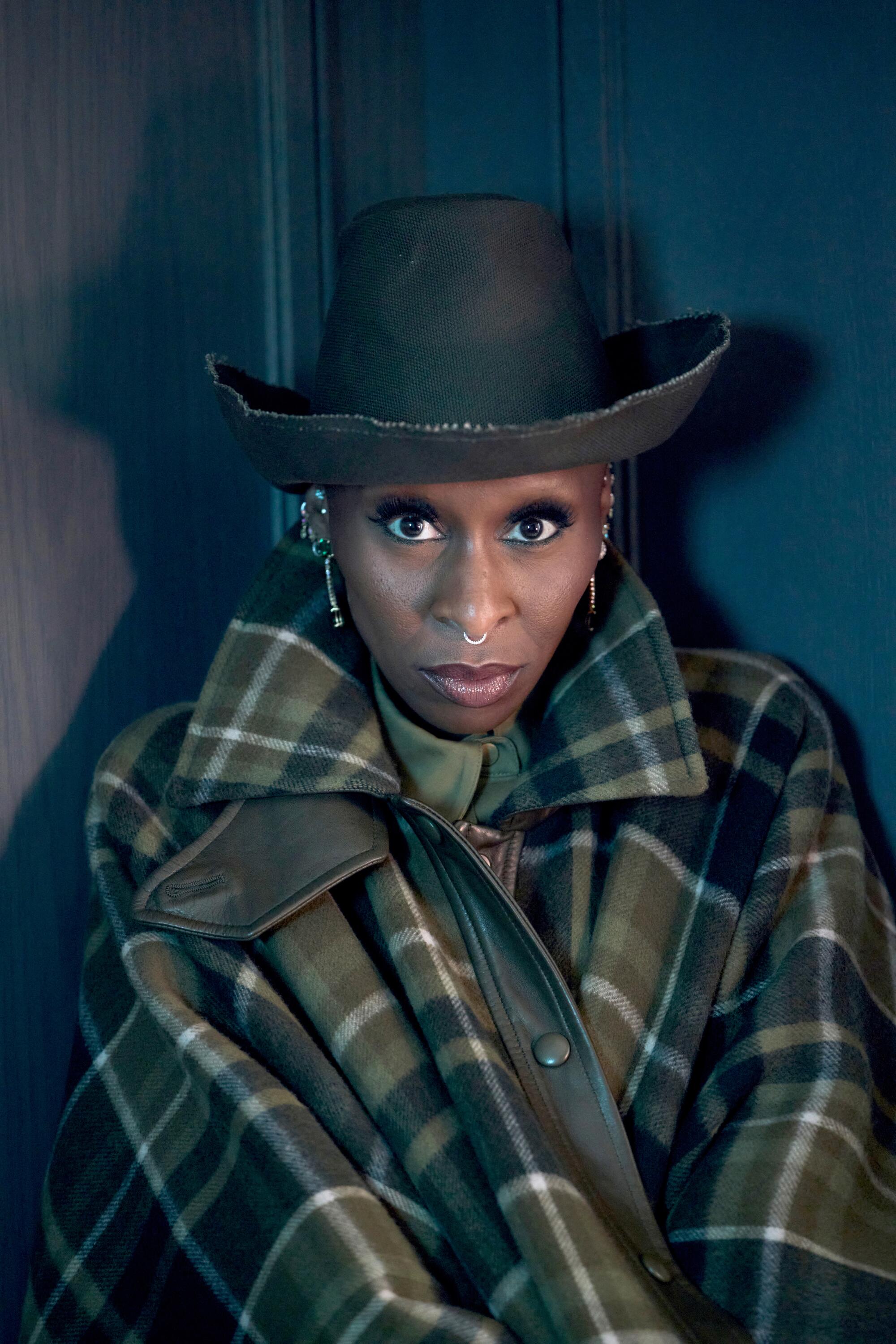 Cynthia Erivo wears a plaid coat and black hat for a portrait.