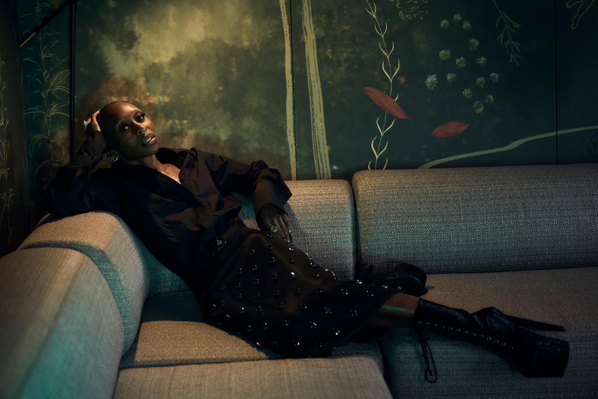 Cynthia Erivo leans back on a sofa for a portrait