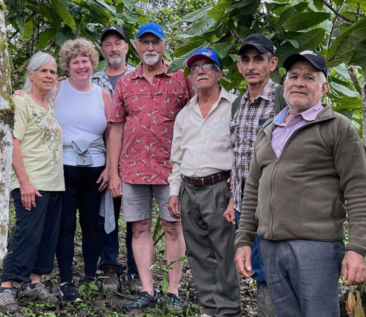 Teresa Sasse standing in front of lush trees for a group photo with another woman and five men