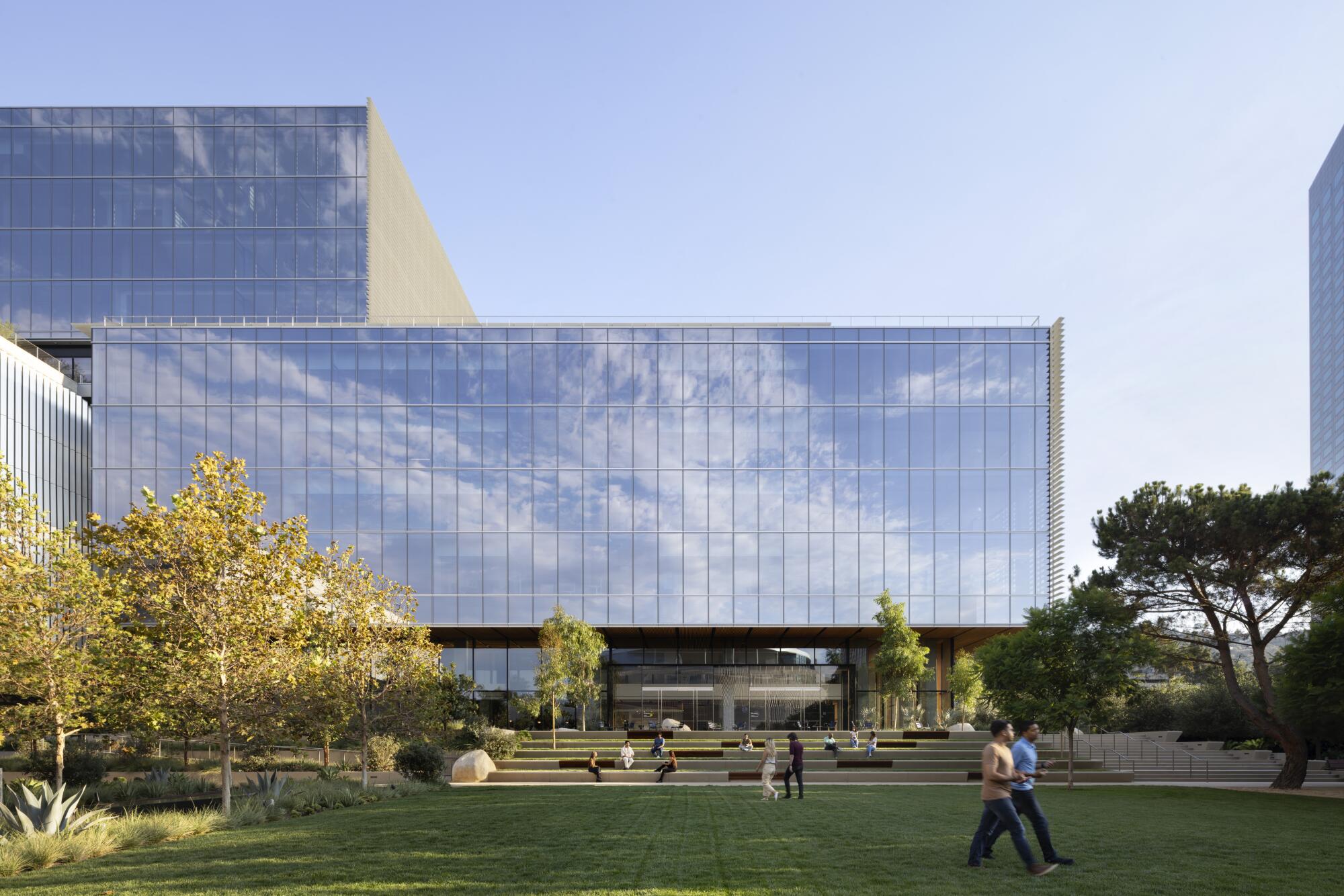 Two cube-shaped glassy office structures rise above a grassy field.