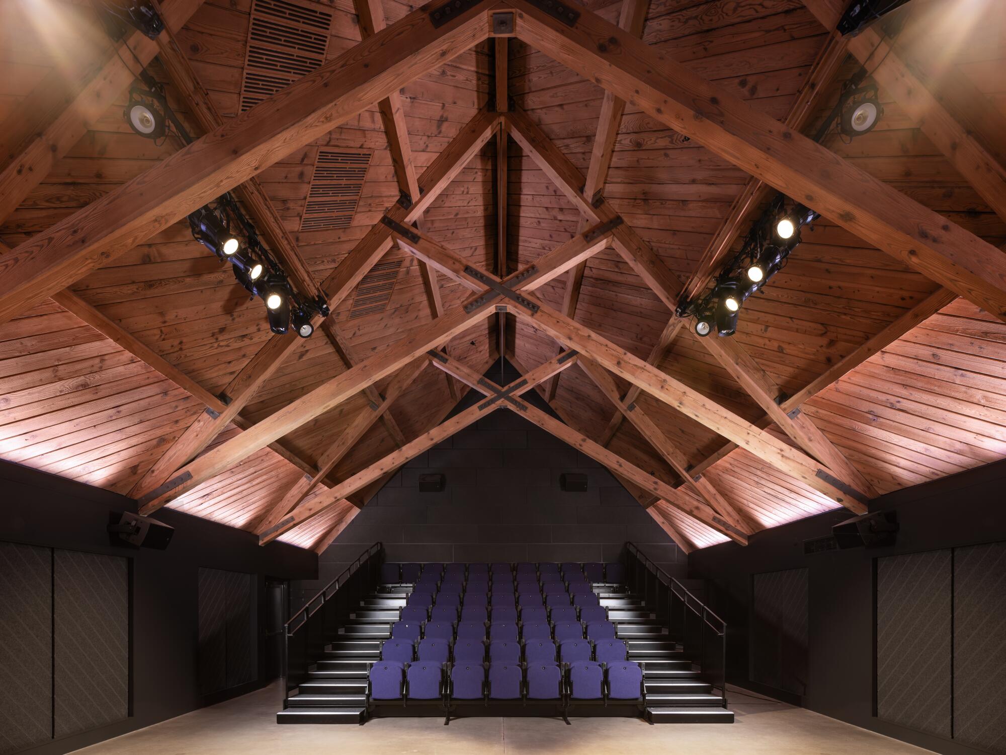 The original wood beams of an A-Frame theater stand above a small, newly renovated theater.