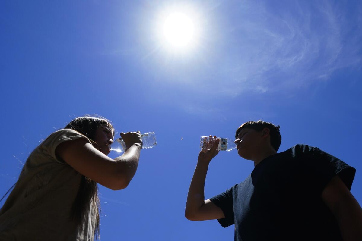 Tony Berastegui Jr., right, and his sister Giselle Berastegui drink water during a historic July 2023 heat wave in Phoenix.