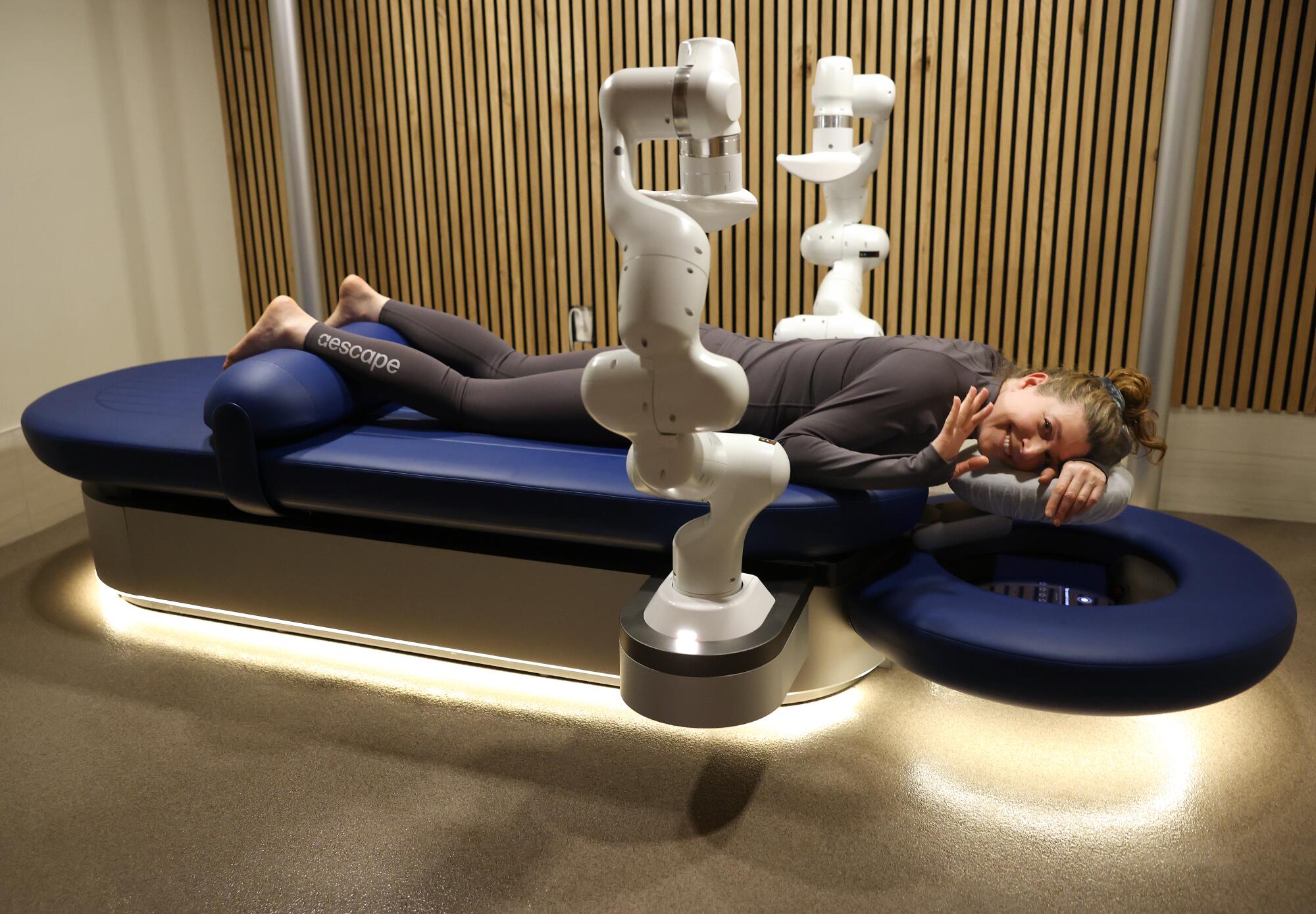 Times reporter Deborah Vankin waves to the camera while on the massage table. 