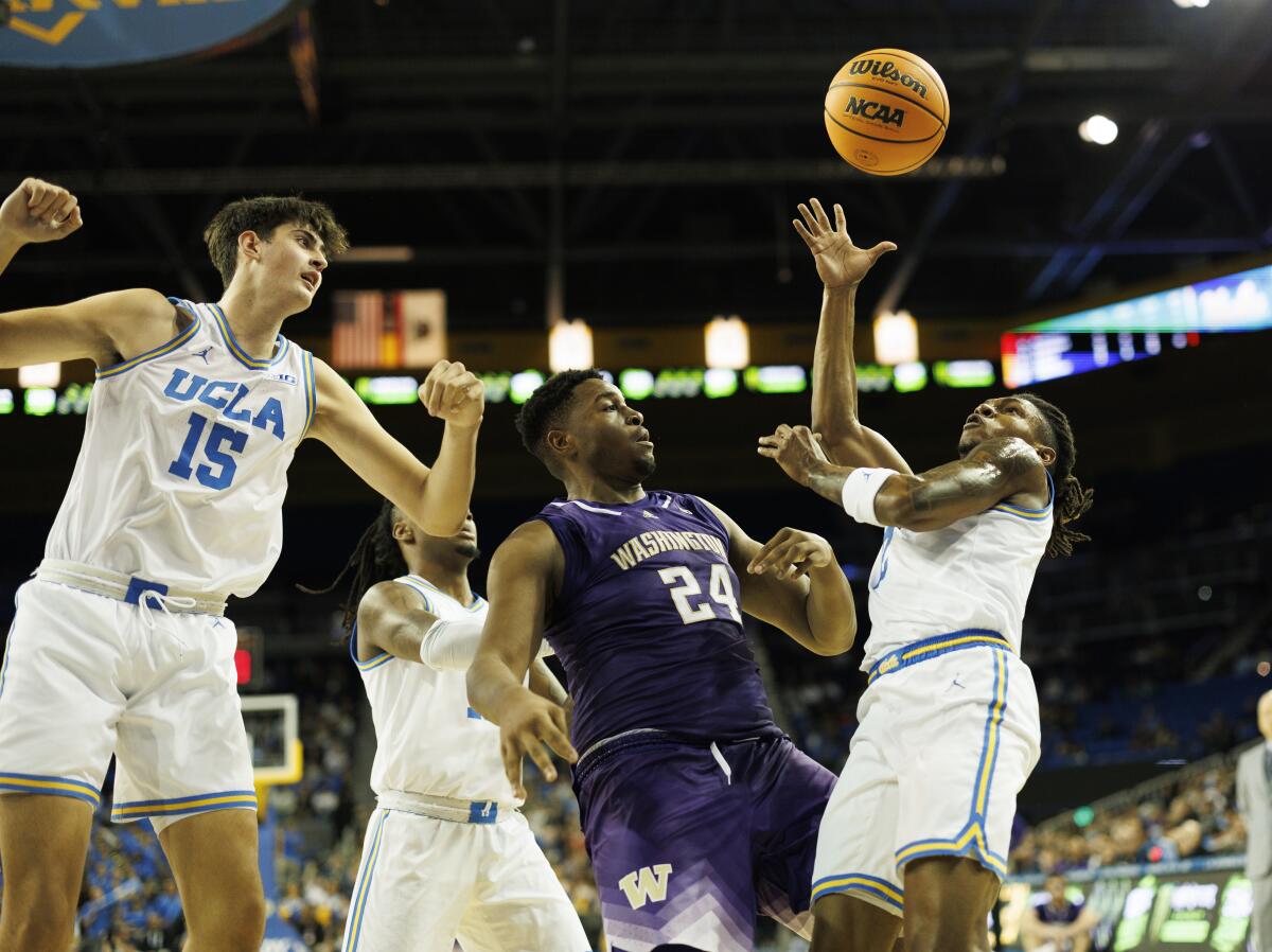 UCLA guard Dylan Andrews grabs a rebound in front of Washington Huskies center KC Ibekwe and UCLA center Aday Mara.