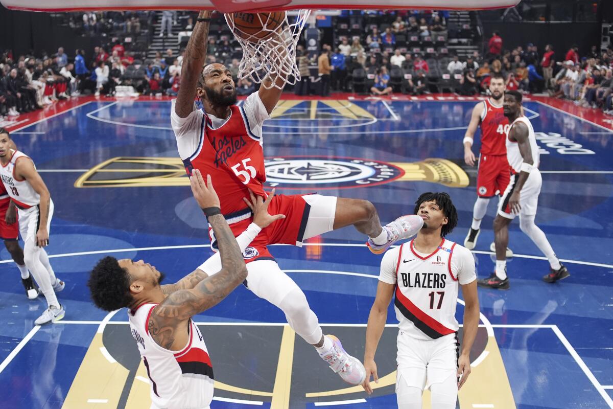 Clippers forward Derrick Jones Jr., center, dunks over Trail Blazers guards Anfernee Simons, left, and Shaedon Sharpe.