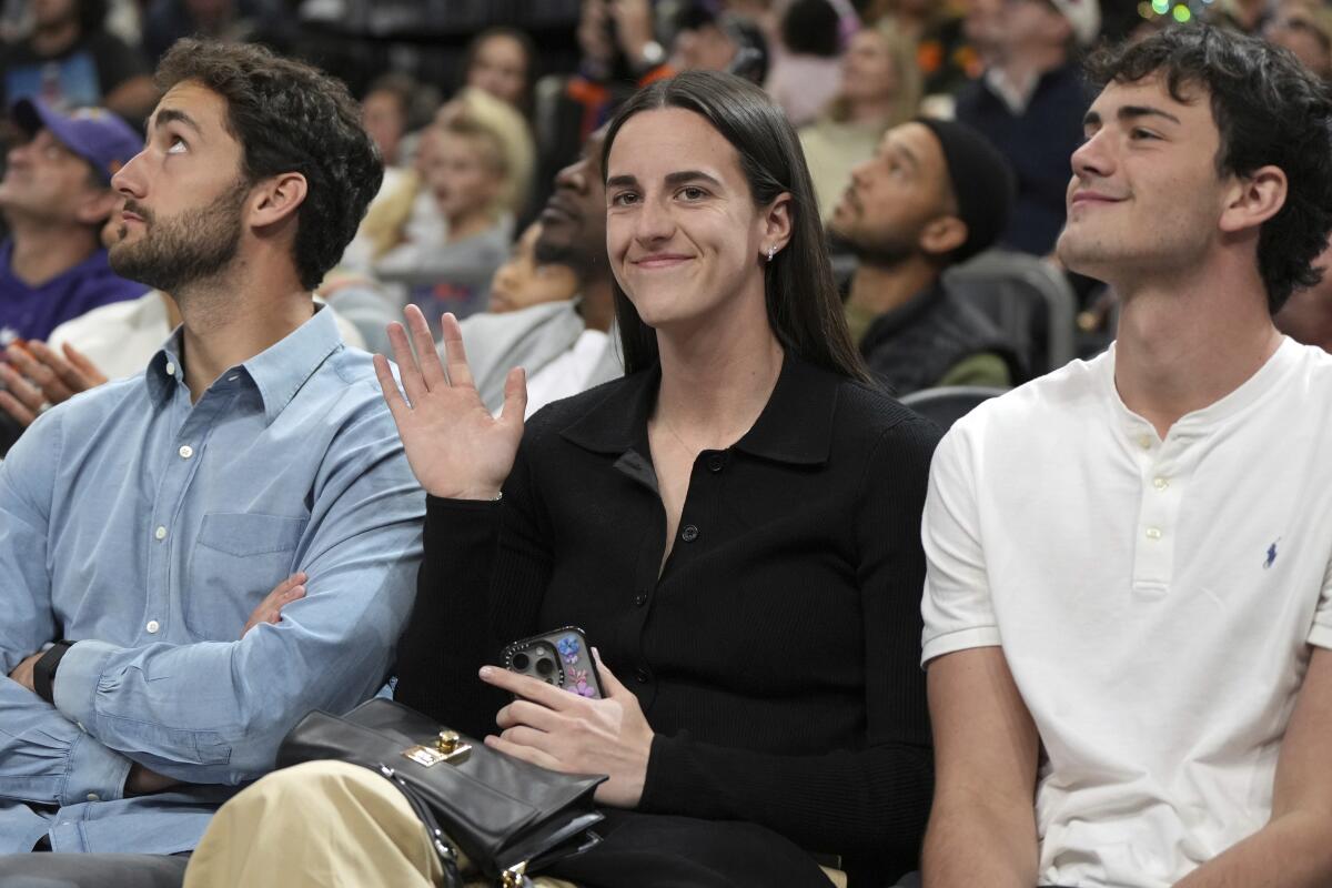 WNBA star Caitlin Clark is sitting down while being introduced to the fans during an NBA game between the Suns and Warriors