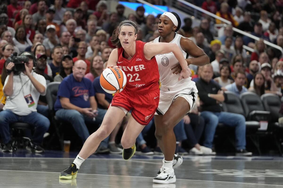 Fever's Caitlin Clark dribbles to the basket with Aces' Jackie Young defending her during a basketball game