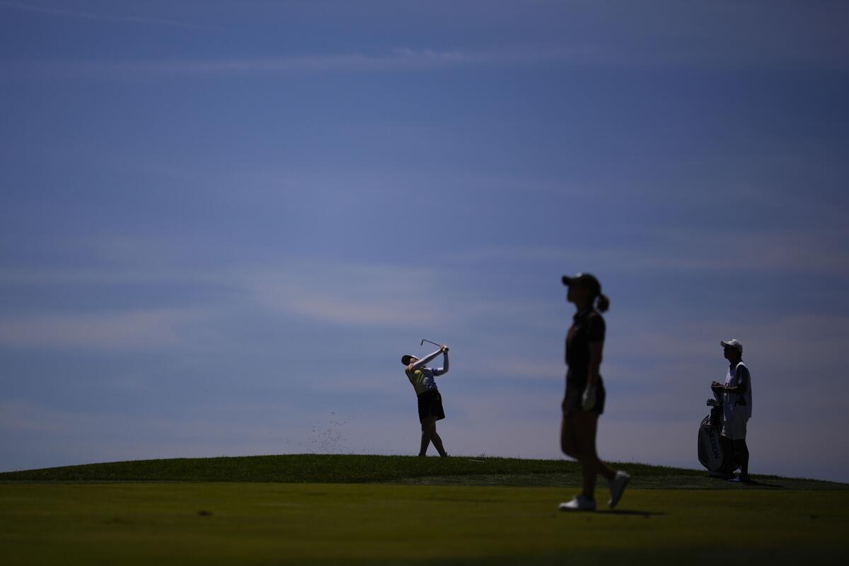 Silhouetted golfers take part in the U.S. Women's Open golf tournament