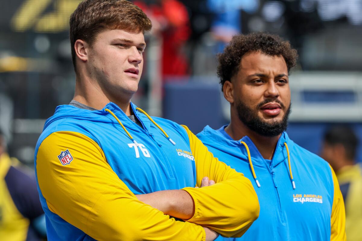 Injured Chargers Joe Alt (left) and Rashawn Slater stand on the sideline during the first game against the Chiefs.