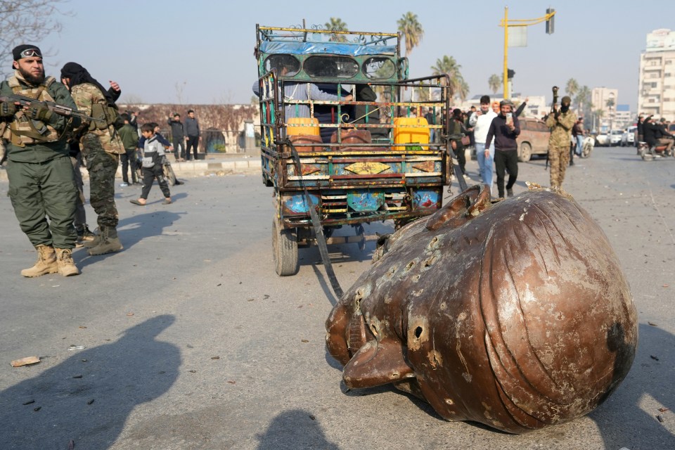 A truck pulls the head of the toppled statue of late Syrian president Hafez al-Assad