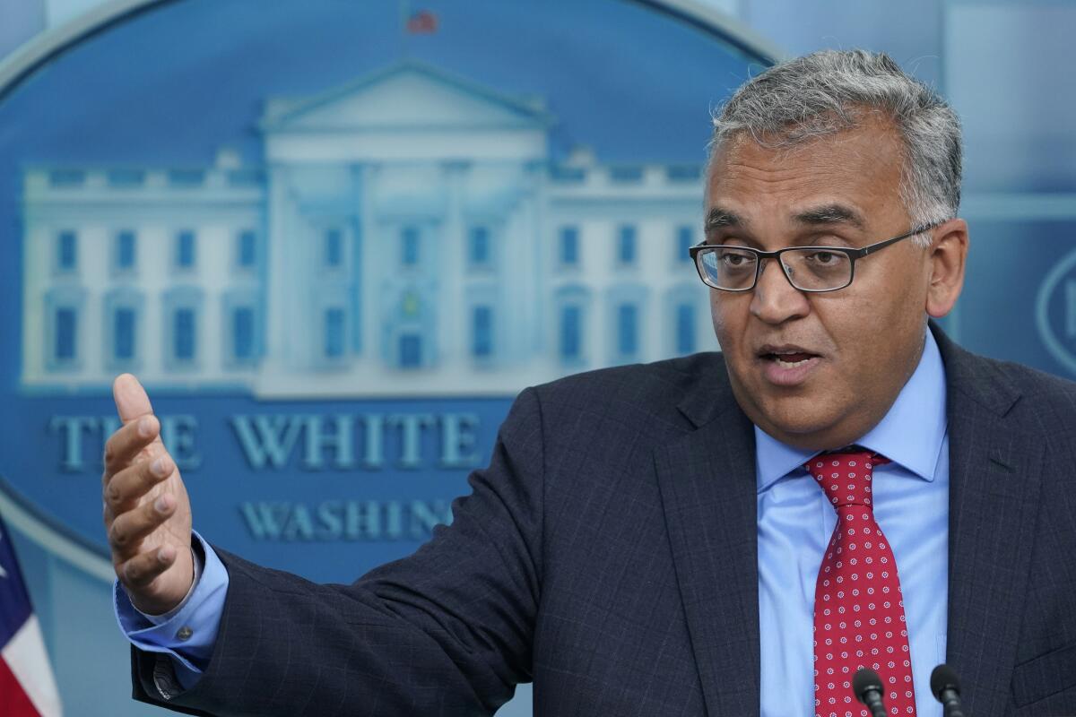 Dr. Ashish Jha gestures while speaking with a White House logo on the wall behind him