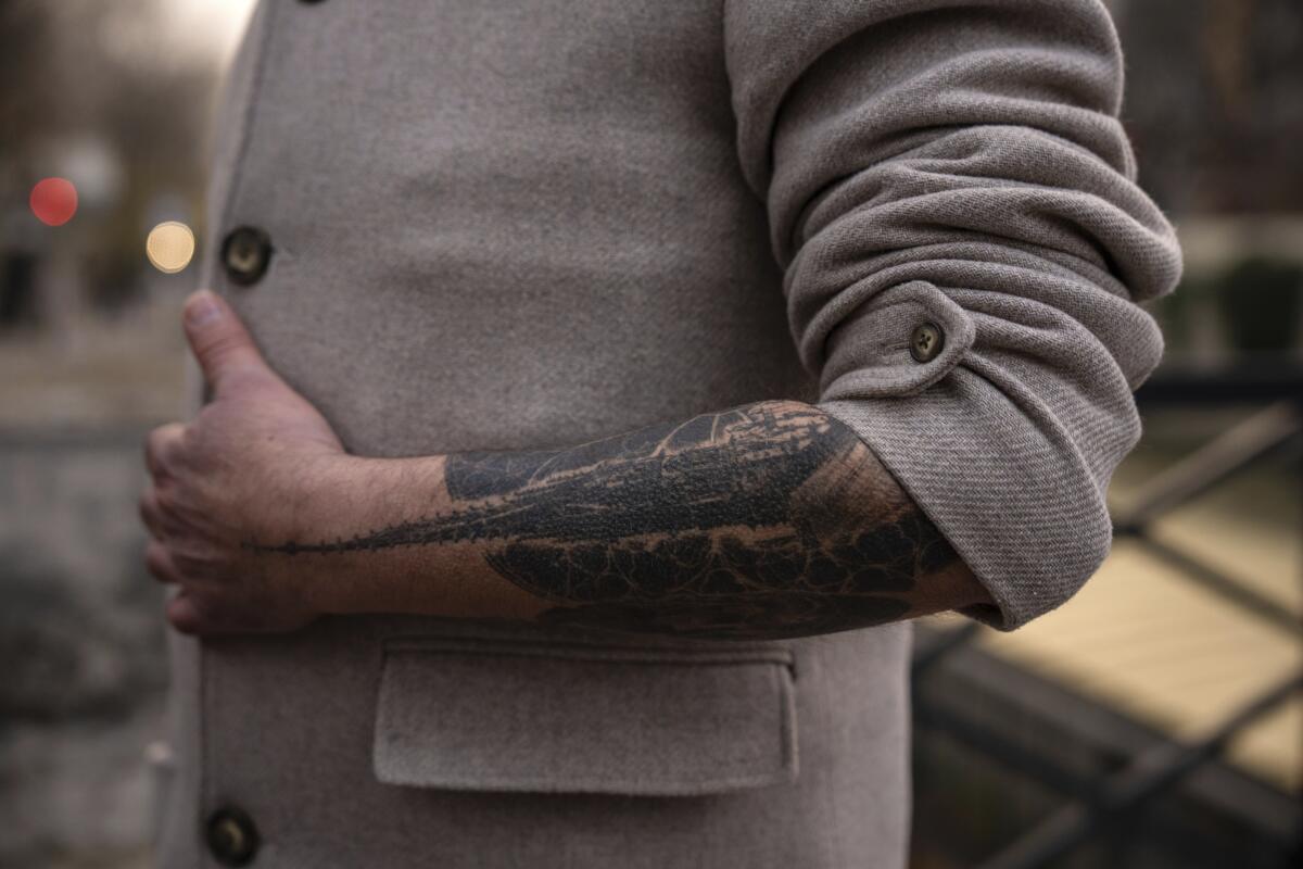 A man's arm with a tattoo featuring the original spire of Notre-Dame cathedral.