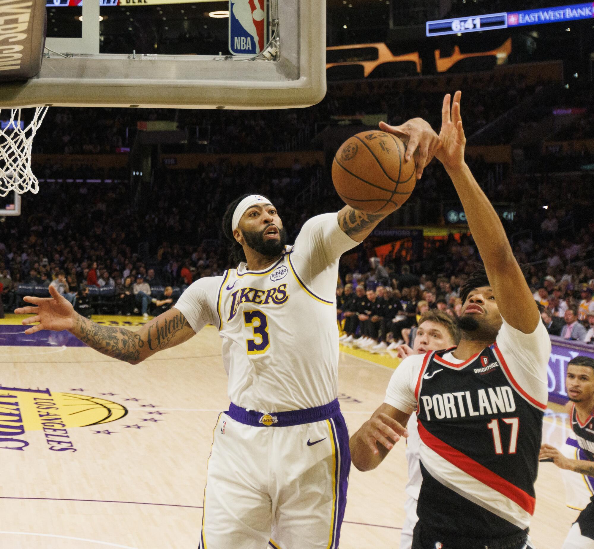 Lakers forward Anthony Davis grabs a rebound in front of Portland Trail Blazers guard Shaedon Sharpe.