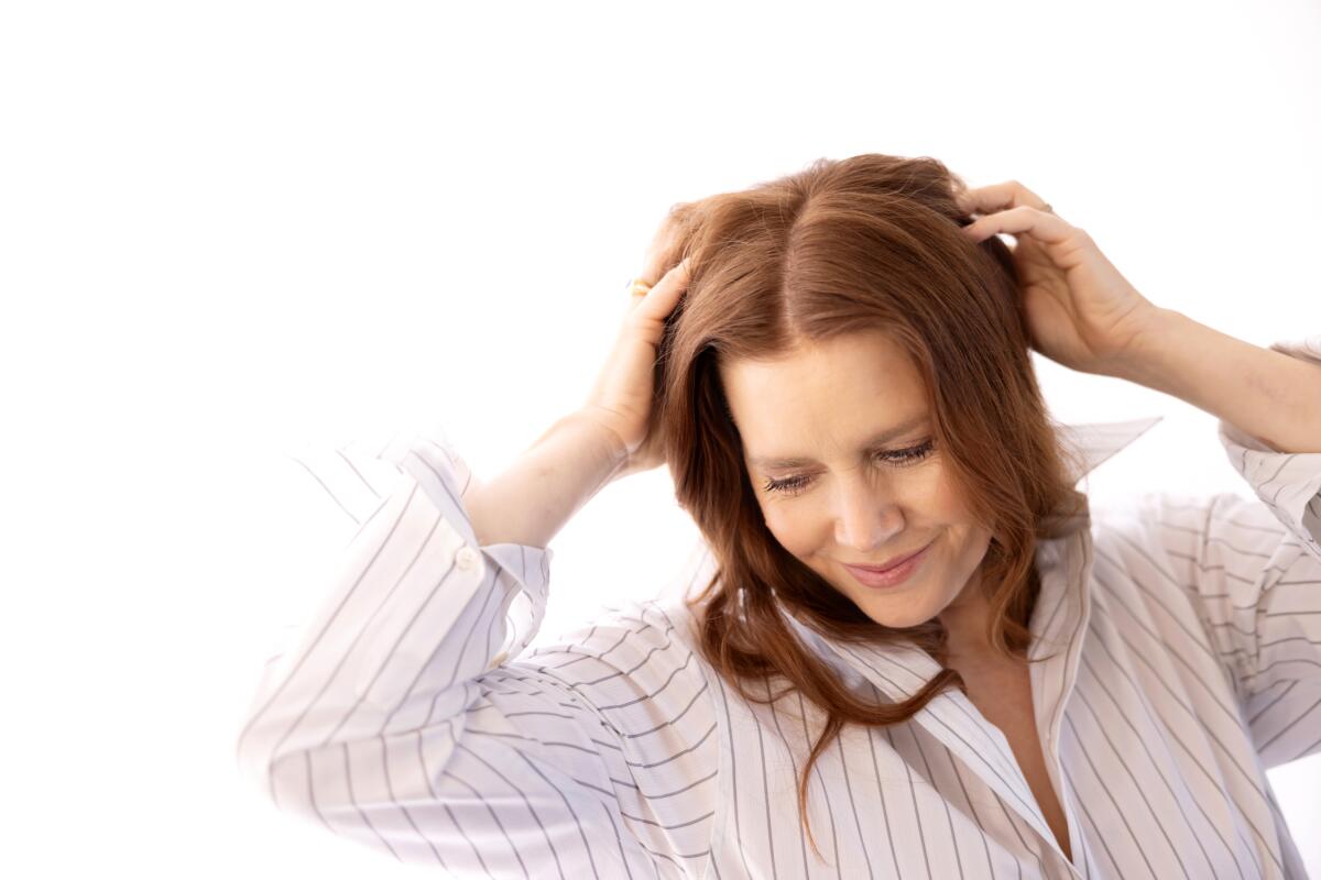 Amy Adams, looking downward with her hands on her head