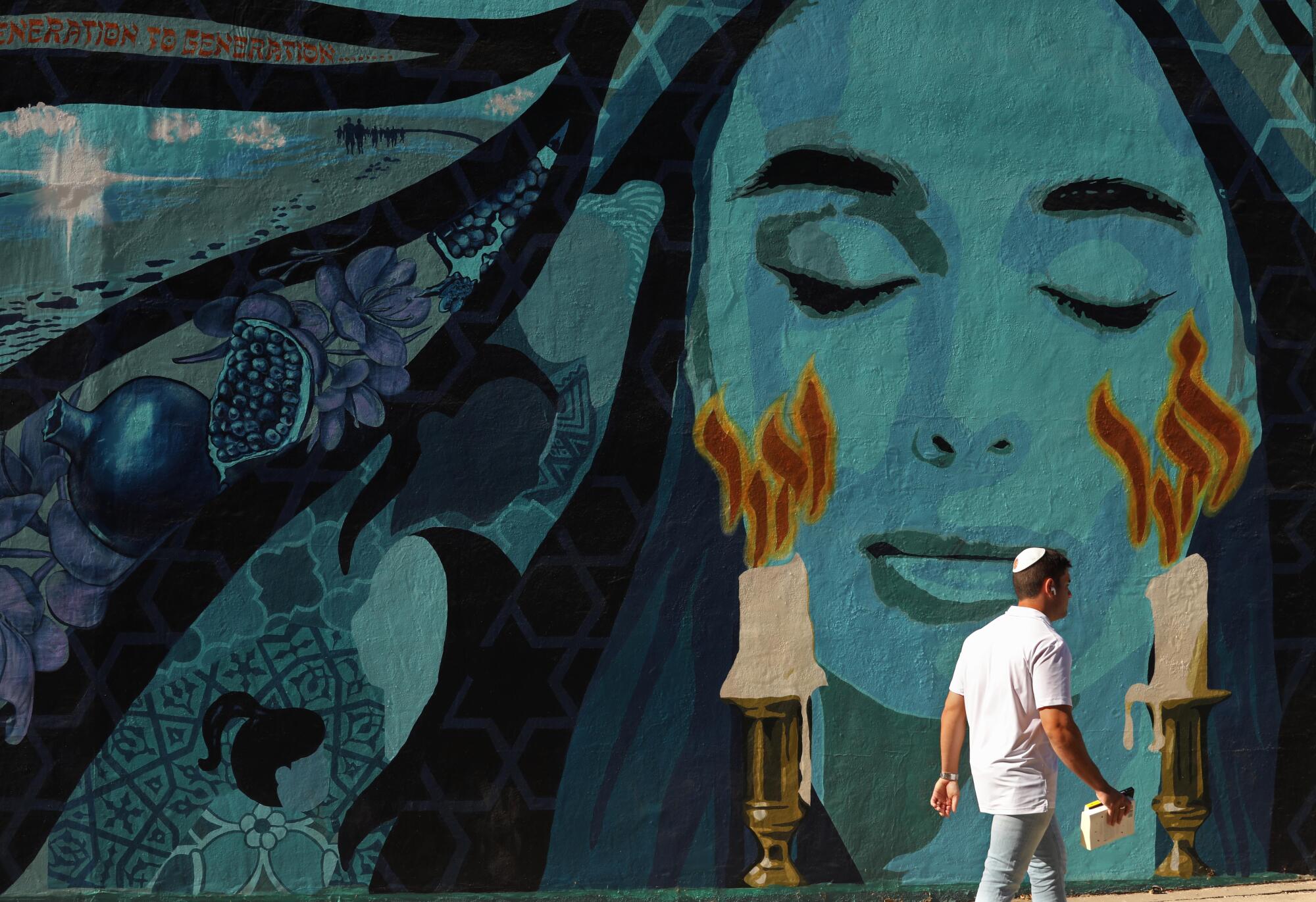 A man walks past a mural of a woman's face.