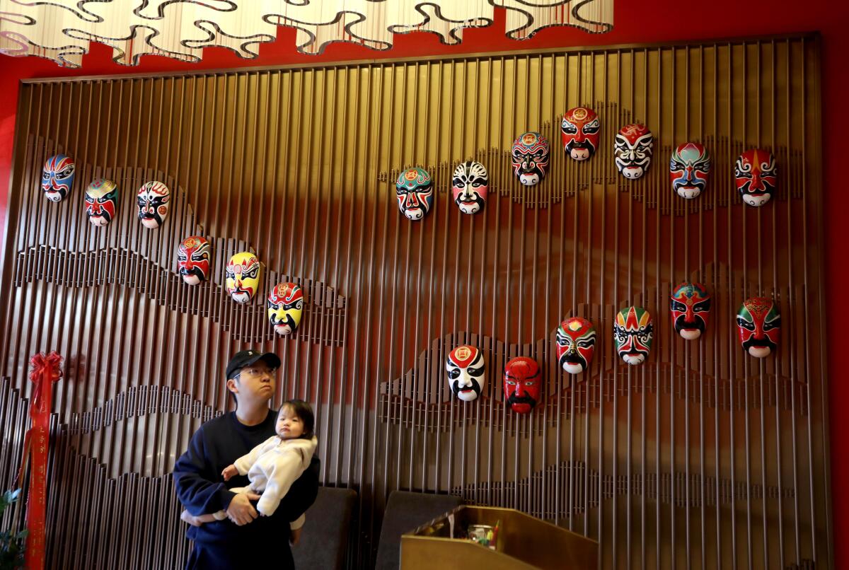 Elliott Chen and his daughter Bella wait for a takeout lunch in the lobby of the Tang Gong restaurant in Arcadia.