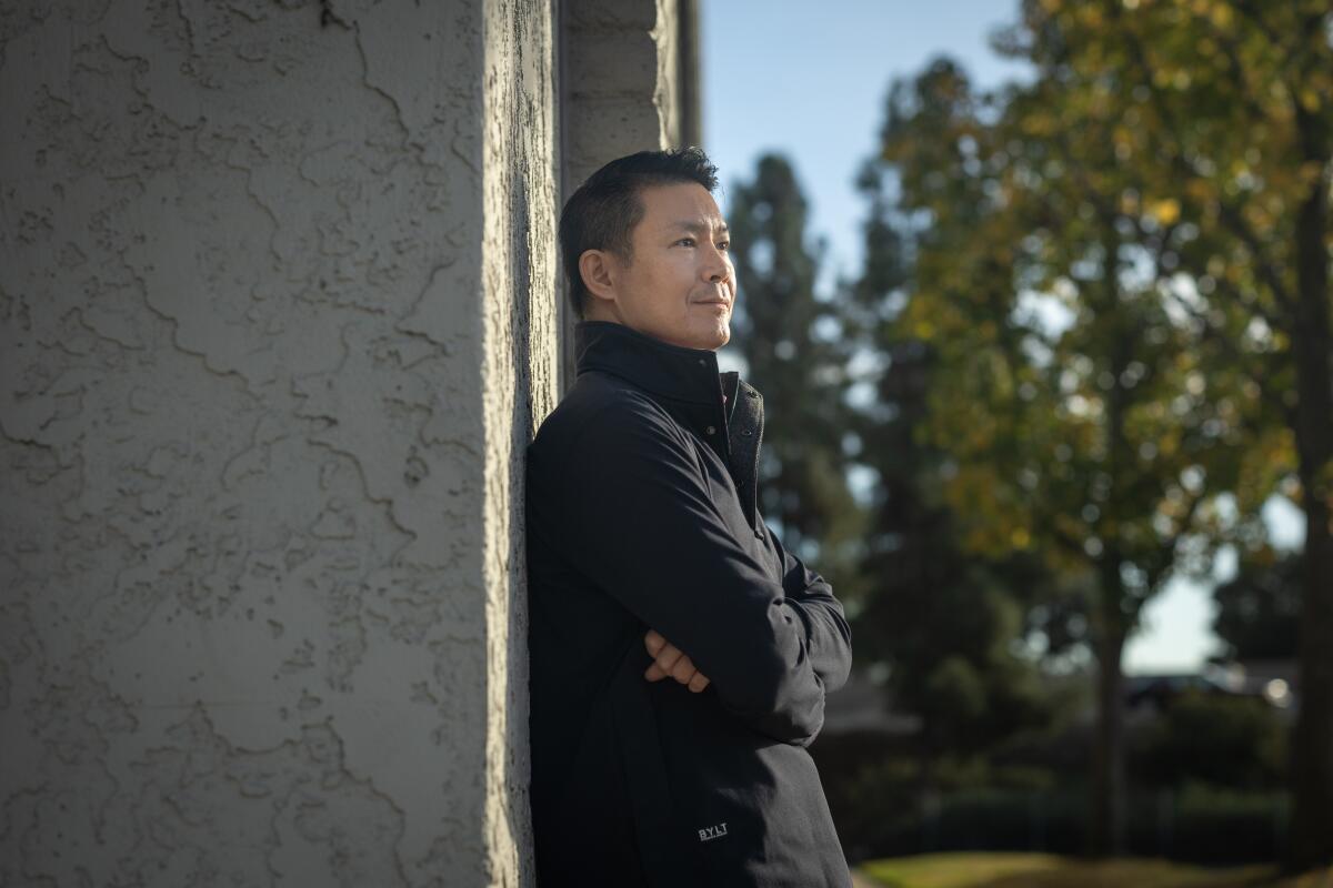 A man leans on the side of a building.