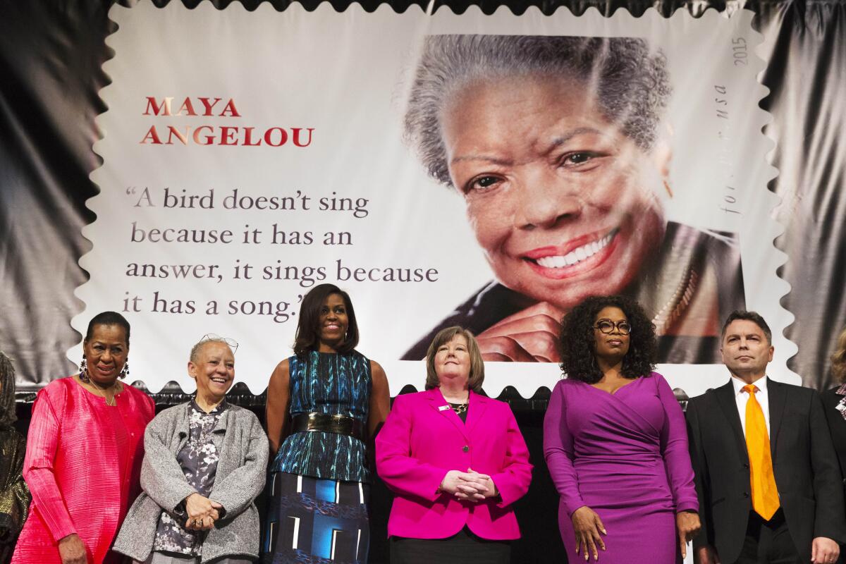 Nikki Giovanni stands in a row of luminaries under a giant Maya Angelou postage stamp.