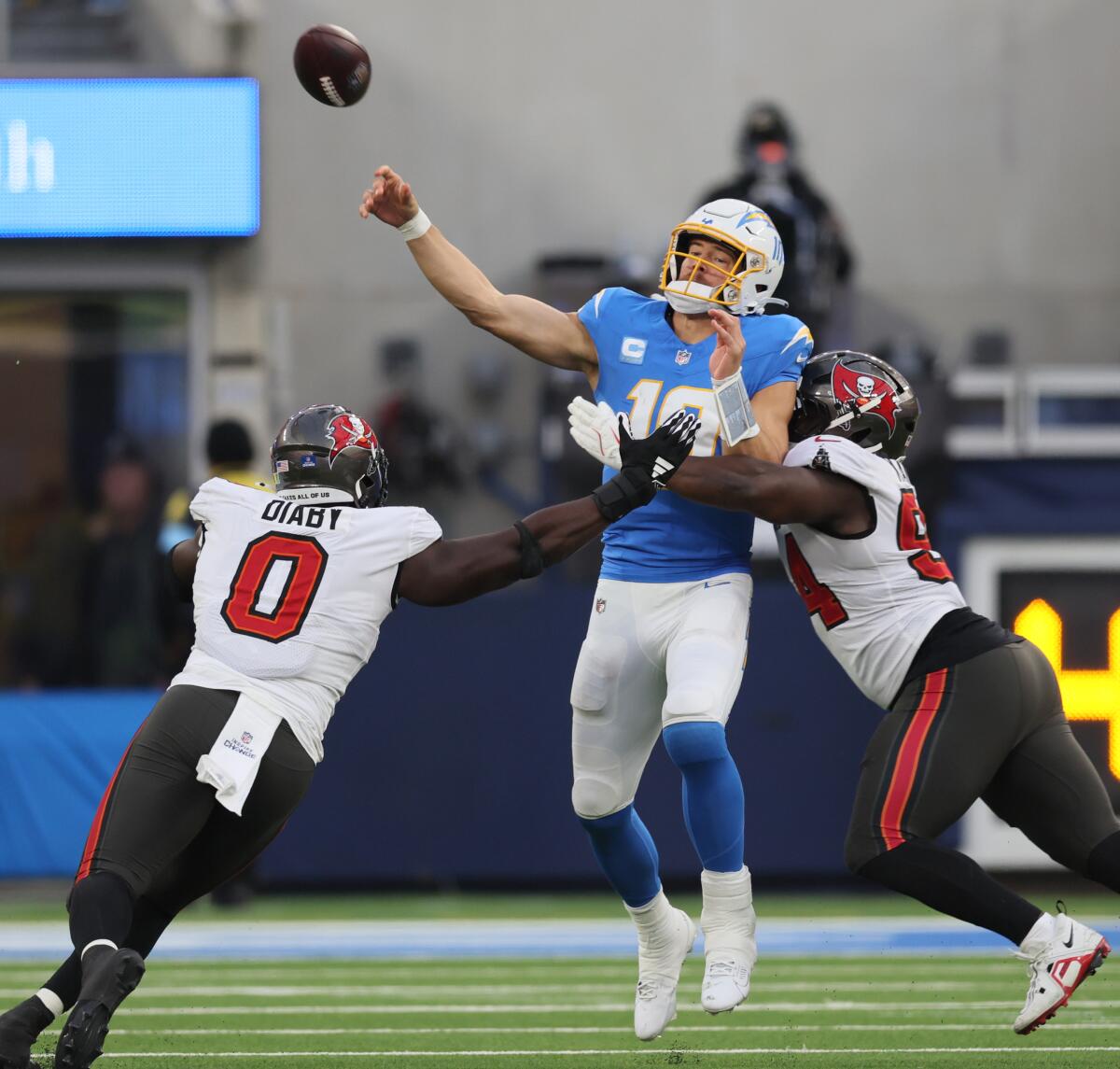 Buccaneers Yaya Diaby (0) and Calijah Kancey (94) converge to hit Chargers quarterback Justin Herbert (10) as he throws.